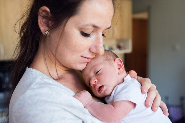 Young mother in kitchen holding baby