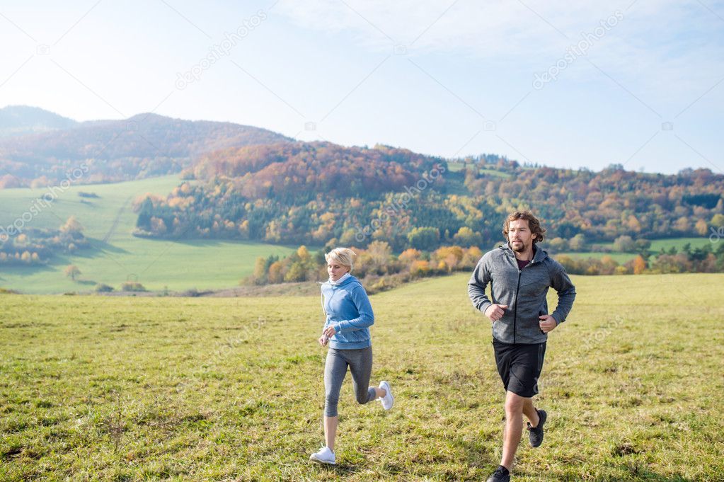 young couple running in autumn nature.