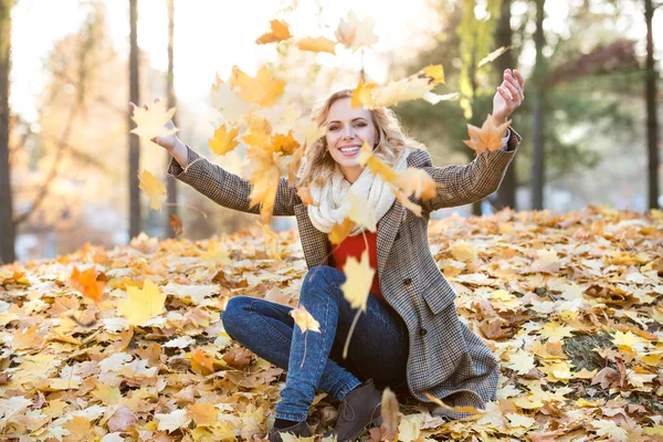 Woman with leaves in autumn park — Stock Photo, Image