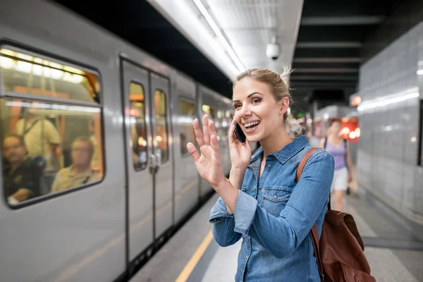 Женщина с телефоном на платформе метро — стоковое фото