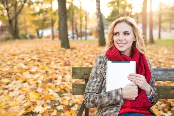 Krásná žena s tabletou v podzimním parku — Stock fotografie