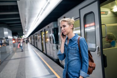 Woman with phone at underground platform clipart