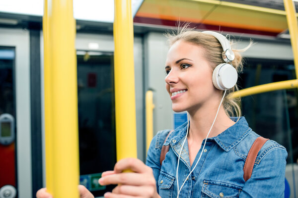 woman with headphones in subway train