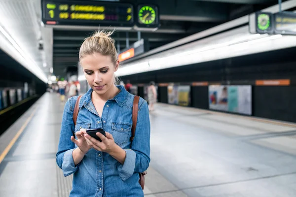 Mujer en la plataforma subterránea con smartphone —  Fotos de Stock