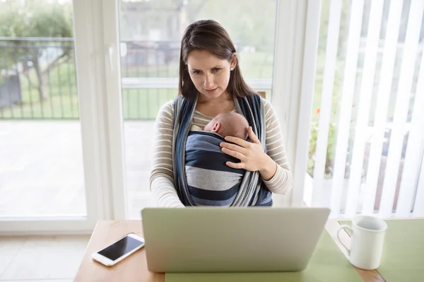 Moeder bedrijf baby, werkt op laptop — Stockfoto