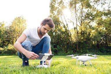 Drone ile genç hipster adam. Güneşli yeşil doğa.