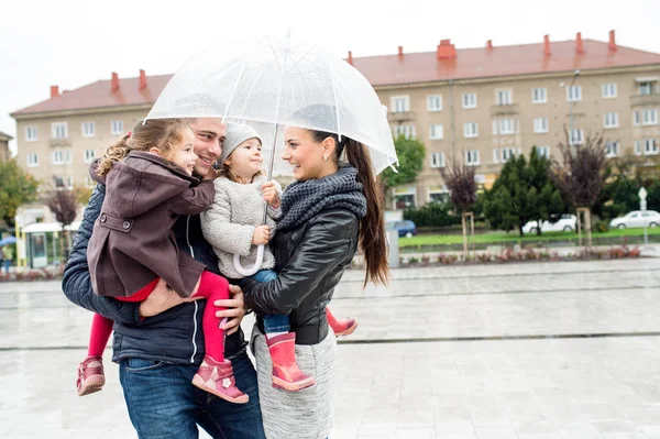 Νεαρή οικογένεια με δύο κόρες κάτω από την ομπρέλα, πόλη — Φωτογραφία Αρχείου