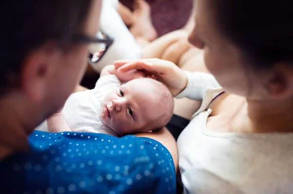 Неузнаваемые родители держат своего новорожденного сына, целуют его — стоковое фото