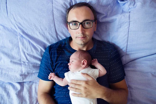 Vater mit seinem neugeborenen Sohn im Bett liegend — Stockfoto