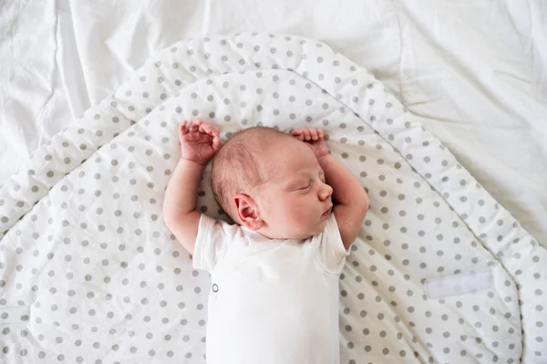 Новорожденный мальчик лежит на кровати, спит, закрывается — стоковое фото