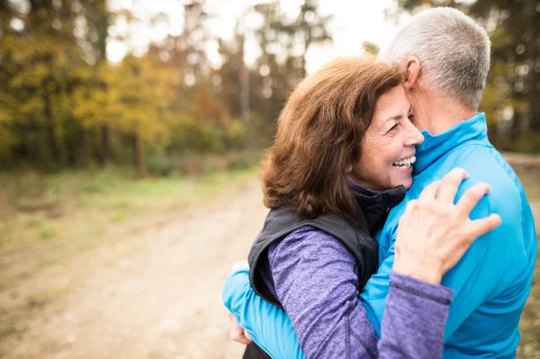 Beautiful senior couple running outside in sunny autumn forest — Stock Photo, Image