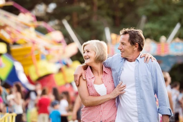 Äldre par på fun fair, kramas. Solig sommar. — Stockfoto
