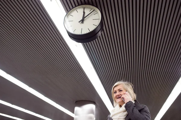 Mulher sênior na plataforma subterrânea, falando por telefone — Fotografia de Stock
