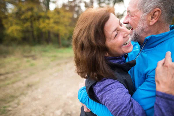 Vacker äldre par kör utanför i soliga höst skog — Stockfoto