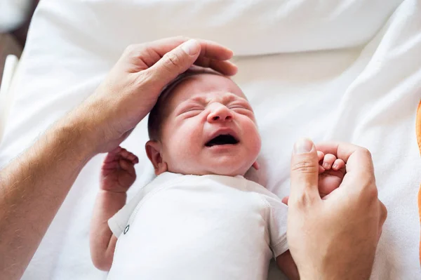 Неузнаваемый отец, ласкающий плачущего новорожденного сына — стоковое фото