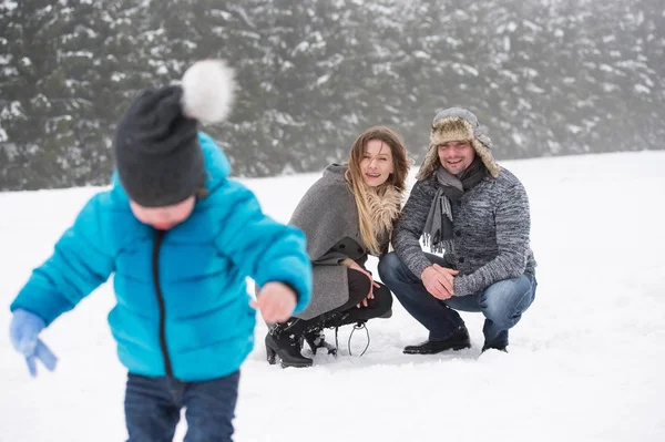 Pai e mãe com seu filho, brincando na neve . — Fotografia de Stock