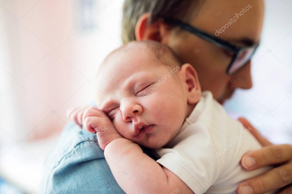 Close up of young father holding his newborn baby son