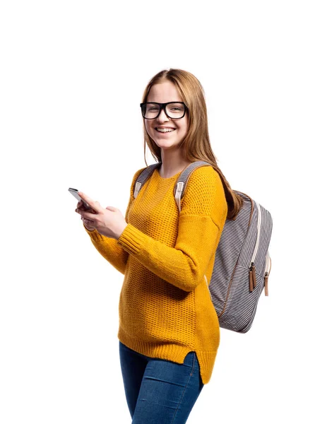 Дівчина в жовтому светрі і окулярах тримає смартфон, ізолат — стокове фото