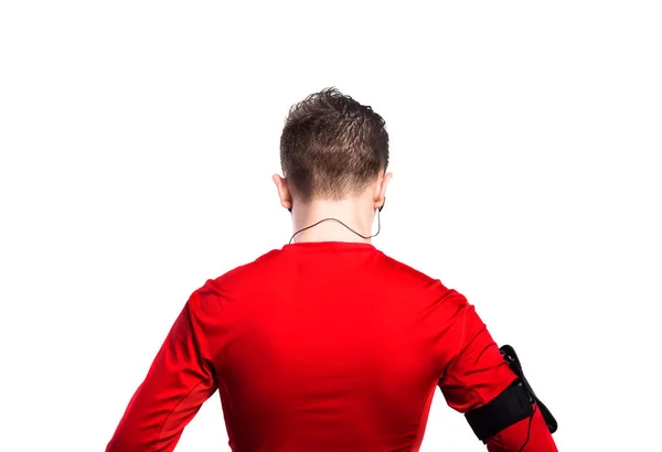 Tonårspojke med hörlurar, i röd sport tröja. Isolerade. — Stockfoto