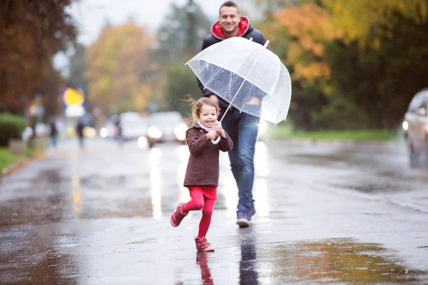 Apa kicsi lánya égisze alatt. Esős nap séta. — Stock Fotó