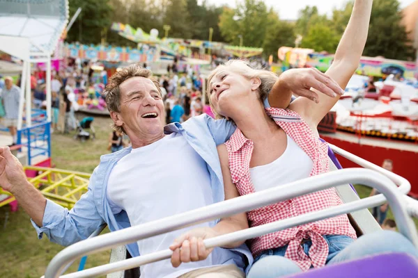 Senior couple on a ride in amusement park — Stock Photo, Image