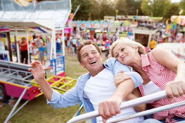 Senior couple on a ride in amusement park — Stock Photo, Image