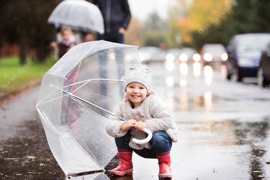 Little girl under the umbrella. Walk on rainy day.