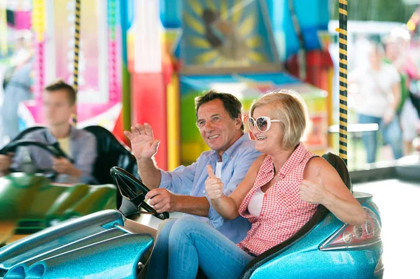 Pareja mayor en el coche de choque en la feria de la diversión —  Fotos de Stock