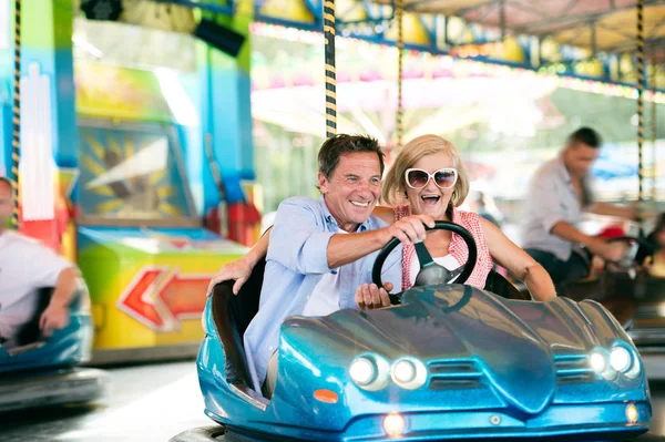 Pareja mayor en el coche de choque en la feria de la diversión —  Fotos de Stock