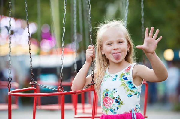 Linda niña en la feria de la diversión, paseo en cadena swing —  Fotos de Stock