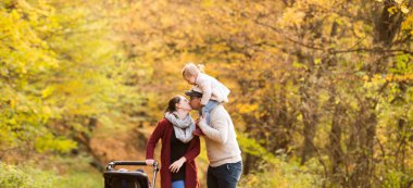 Güzel genç aile sonbahar ormandaki bir yolda.