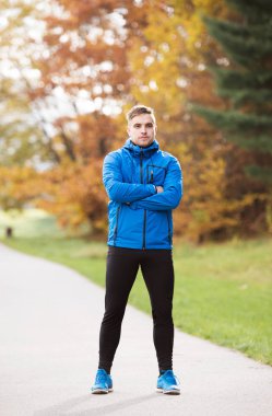 Genç atlet sonbahar park ayakta beton yol