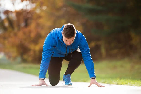 Young runner in park on asphalt path in steady position — Stock Photo, Image