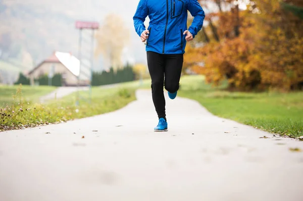 Atleta irriconoscibile nel parco autunnale che corre su un sentiero in cemento — Foto Stock