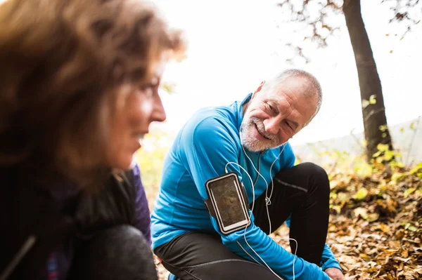 Äldre löpare i naturen, knyta skosnören. Mannen med smartphone. — Stockfoto