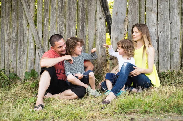 Красива молода сім'я проти старого дерев'яного паркану. Літня природа . — стокове фото