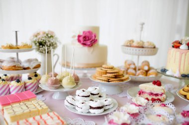 Table with loads of cakes, cupcakes, cookies and cakepops. clipart
