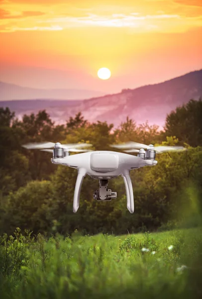 Hovering drone taking pictures of green nature at sunset