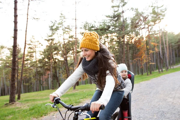 Giovane madre e figlia in bicicletta nel parco autunnale — Foto Stock