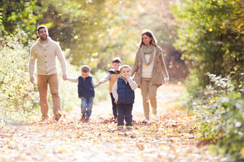 Beautiful young family on a walk in autumn forest.