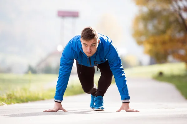 Jonge atleet in park op het asfalt pad in stabiele positie — Stockfoto