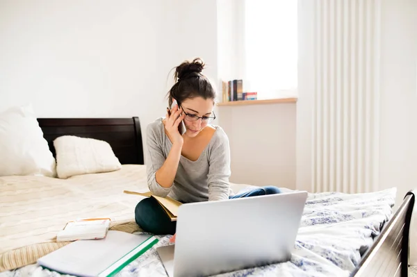 Mujer sentada en la cama, trabajando en el portátil, llamando. Oficina en casa . — Foto de Stock