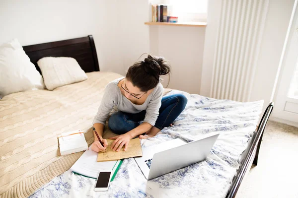 Hermosa joven sentada en la cama, trabajando. Oficina en casa. — Foto de Stock