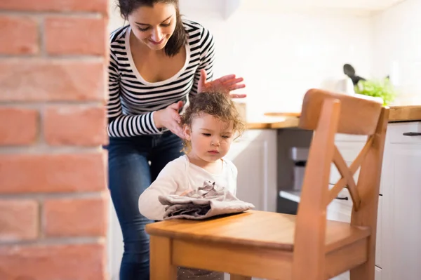 Madre con hija en la cocina, niña limpiando silla —  Fotos de Stock