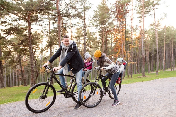 Ung familj i varma kläder cykling i höst park — Stockfoto