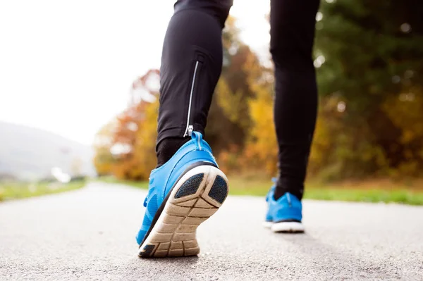 Jambes d'un coureur méconnaissable debout sur un chemin en béton, à proximité u — Photo