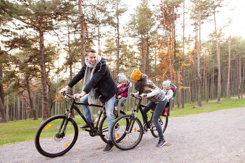 Young family in warm clothes cycling in autumn park