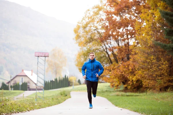 Giovane affascinante atleta hipster in esecuzione contro colorato autunno n — Foto Stock