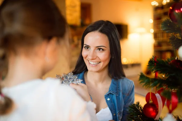 Young mother with daugter decorating Christmas tree together. — Stock Photo, Image
