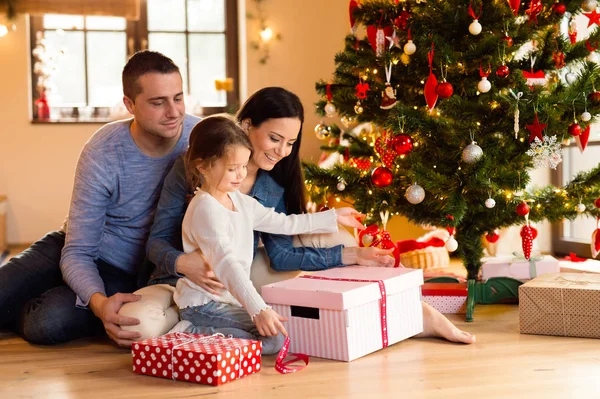 Junge Familie mit Tochter am heimischen Weihnachtsbaum. — Stockfoto
